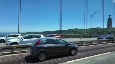 Lizbon Köprüsü 'nde uçan arabalarla yol trafiği ve şehir arka planıyla seyahat edin.