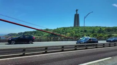 Lizbon şehir manzarası, köprüde hareket halindeki arabalarla ve şehir içi seyahat sahneleriyle görüldü.