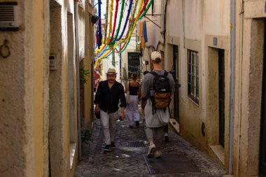 İnsanlar Lizbon, Portekiz 'de renkli bir sokakta geziniyorlar.