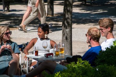 Arkadaşlar güneşli bir öğleden sonra açık bir kafede içki içiyorlar.