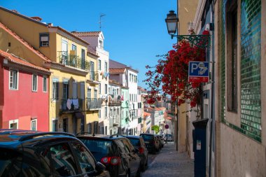 Lizbon, Portekiz 'de renkli binaların ve park edilmiş arabaların olduğu büyüleyici bir sokak manzarası.
