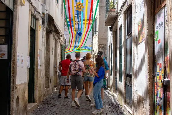 Portekiz, Lizbon 'da dar bir sokakta renkli kurdeleler altında yürüyen insanlar..