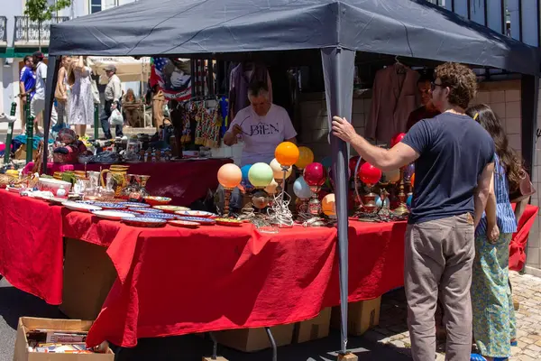 Çeşitli malların sergilendiği hareketli bir sokak piyasa sahnesi.
