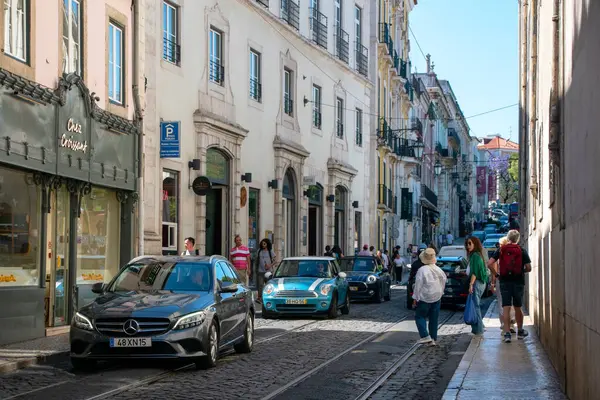 Lizbon, Portekiz 'de arabaları ve yayaları olan hareketli bir sokak sahnesi.