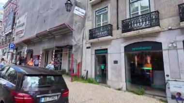 Lizbon Portekiz 'de tramvay yolculuğu, eski evleri ve dar kaldırımlı yolları olan bir sokak.