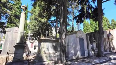 Moody kırık taşlar ve gölgelerle mezarlıkta yürüyor.