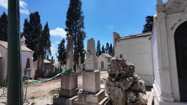 Sessiz mezarlık, yumuşak gökyüzünün altındaki mezar çizgili yolda yürüyor.