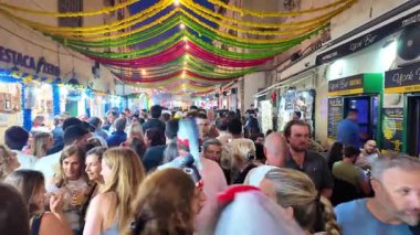 Portekiz sokaklarında insanlar dans ediyor, sardalyalar ızgara yapıyor, renkli Aziz Anthony süslemeleri ve kutlamaları yapıyorlar.