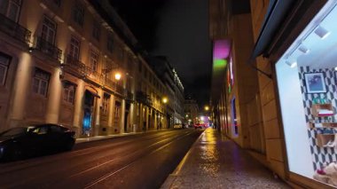 Lizbon 'da eski binalar ve ışıklarla dolu bir gece sokağı.