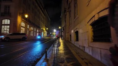 POV gece Lizbon 'da yürürken parlak sarı sokak lambalarını geçiyor.