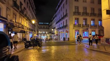 Parlak lambalar ve geleneksel binalarla dolu Lizbon şehir gece hayatı sahnesi
