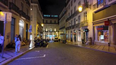 Neon ışıkları ve kaldırımlı yürüyüş perspektifi olan canlı Lizbon gece caddesi