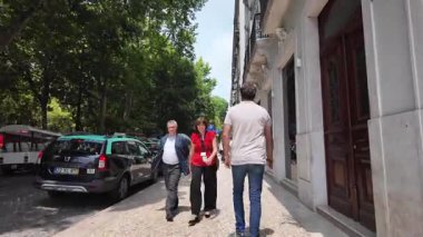 Güneşli bir yaz gününde insanlar Lizbon sokaklarında eski kasaba manzaralarıyla yürüyorlar.