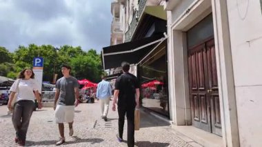 Lizbon 'un tarihi merkezinde Portekiz cazibesi ve güneşiyle yürüyen insanlar.