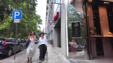 Geleneksel binalar ve yürüyen insanlarla güneşli Lizbon sokak manzarası