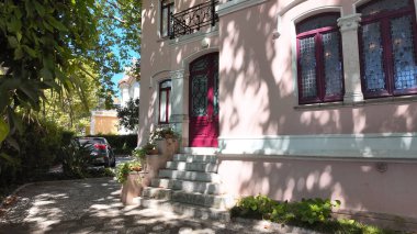 Kırmızı kapısı ve basamakları olan zarif pembe bir ev.