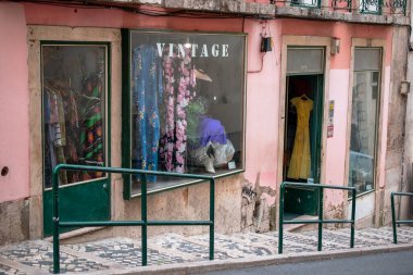 Pencere vitrinleri ve pembe bir binanın açık kapısı olan bir vintage mağazası.