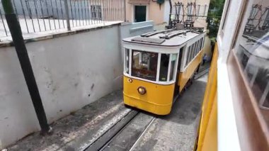 Hareketli bir Lizbon fünikülünün içinden Portekiz 'in eski kentsel alanındaki dik bir pistte başka bir vintage tramvayın geçişini izleyin.