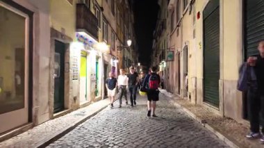 Bairro Alto Lizbon 'da turistlerin yürüdüğü canlı bir gece hayatı, neon ışıkları, yüksek sesli müzik ve sokak içkileri