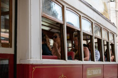 İnsanlar klasik bir tramvayın içinde, şehirde gezintiden zevk alıyorlar..