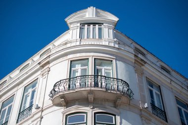 Zarif beyaz bina köşesi süslemeli balkon ve açık mavi gökyüzü