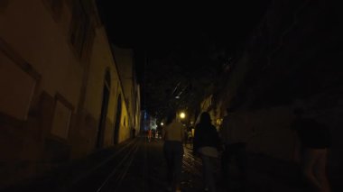 Night walk in Lisbon city center with lively summer crowds and glowing lights in warm evening atmosphere