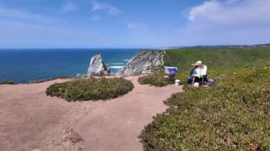 Portekiz kayalıkları boyunca deniz manzaralı ve uzak ufku olan engebeli bir yol.