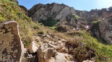 Portekiz 'de uçurumun kenarında yürüyorum. Okyanus rüzgarları ve kayalık manzaralı.
