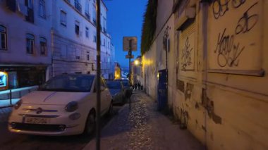 Akşam Lizbon caddesinde yürüyorum. Sıcak ışıklarla ve tatil atmosferiyle tarihi bir yer.