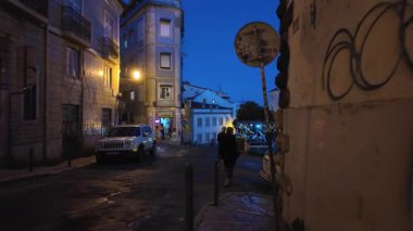 Lizbon tarihi merkezi alacakaranlıkta renkli evler ve parlayan sokak lambalarıyla yürüyor