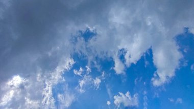 Mavi gökyüzü, beyaz bulutlar gökyüzünde kayboluyor, güneş bulutların arasından parlıyor bu resimde, dramatik gökyüzü bulutları