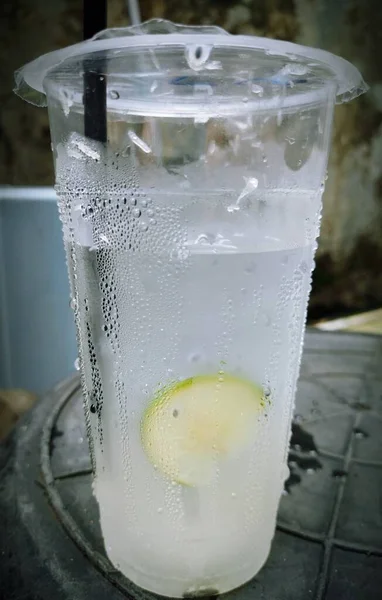 A cup of iced sweet lemon water with black straw