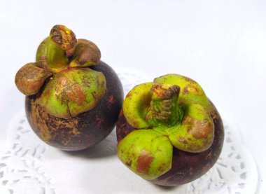 Endonezya 'da Buah Manggis olarak bilinen beyaz bir arka planda izole edilmiş iki mangosen meyve resmi.