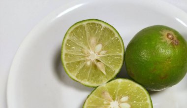 Tüm limonu kapat ve beyaz arka planda izole edilmiş beyaz bir kasede yarım limon kes.