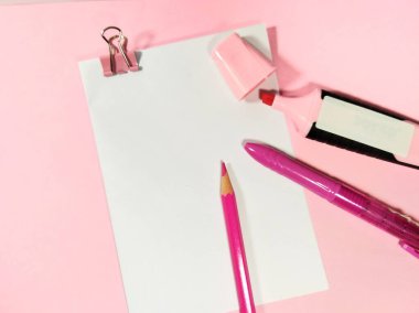 Pembe ataç, kalem rengi, kalem ve fosforlu beyaz bir kağıt, pembe arka planda izole edilmiş.