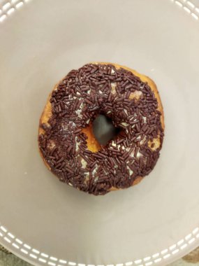 Çikolatalı Donut 'ın gri bir tabakta üst görüntüsünü kapat.