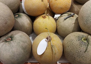 Bir süpermarket tezgahına istiflenmiş kavun yığını.