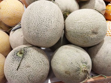 Bir market tezgahına istiflenmiş olgun kavunların yakın çekimi.