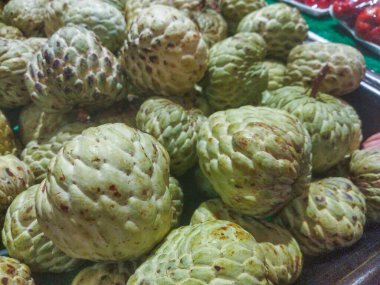 Bir markette sergilenen bir avuç taze yeşil muhallebi elması. Meyvelerin pürüzlü bir dokusu ve tatlı, kremalı bir tadı vardır.