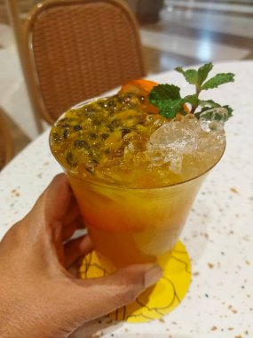 Tutku meyvesi, portakal ve nane ile ferahlatıcı bir tropikal kokteyl. İçki buzda servis edilir ve bir dilim portakal ve nane yaprağı ile süslenir.