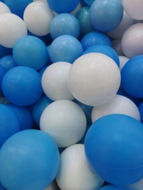 Mavi ve beyaz plastik toplarla dolu bir top havuzunun yakın plan çekimi canlı ve neşeli bir doku yaratıyor.