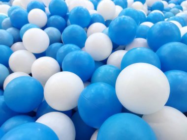 Mavi ve beyaz plastik toplarla dolu bir top havuzunun yakın plan çekimi canlı ve neşeli bir doku yaratıyor.