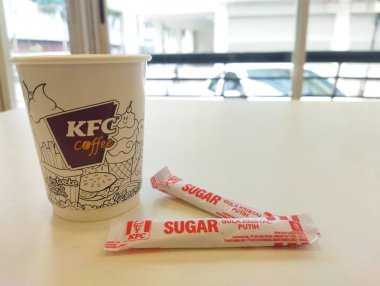 Jakarta - 1 Nisan 2025: KFC kahve fincanının beyaz bir masada iki şeker kesesi ile durgun bir fotoğrafı