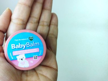 Jakarta - 12 Nisan 2025: Vicks Bebek Merhemi 'nin bir insanın elinde tutulan pembe ve mavi bir konteynırın yakın çekimi