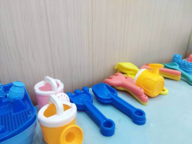 Çocuklar için açık mavi bir yüzeye renkli plastik kum oyuncakları serpiştirilmiştir.