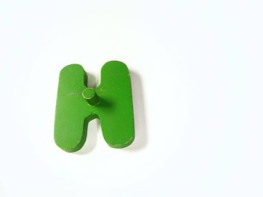 Yakın plan çekimde, beyaz üzerine izole edilmiş, H harfi şeklinde sert, canlı, yeşil bir tahta nesne bulunur.