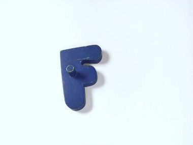 Yakın çekim, koyu mavi tahta bir nesne içerir. Beyaz üzerinde izole edilmiş, F harfi şeklindedir.