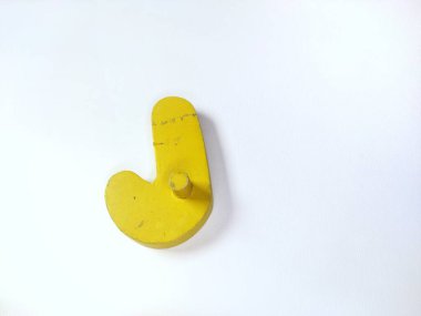 Yakın çekim, beyaz üzerinde izole edilmiş J harfi şeklinde saf, parlak sarı tahta bir nesne içerir.