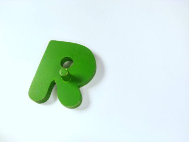 Yakın plan çekimde, beyaz üzerinde izole edilmiş R harfi şeklinde sert, canlı, yeşil tahta bir nesne bulunur.