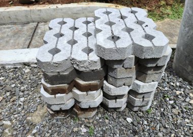 Yığılmış gri çimen patikaları (beton bloklar) birbirine kenetlenmiş bir desen ile, çakıl yüzeyinde yatmaktadır